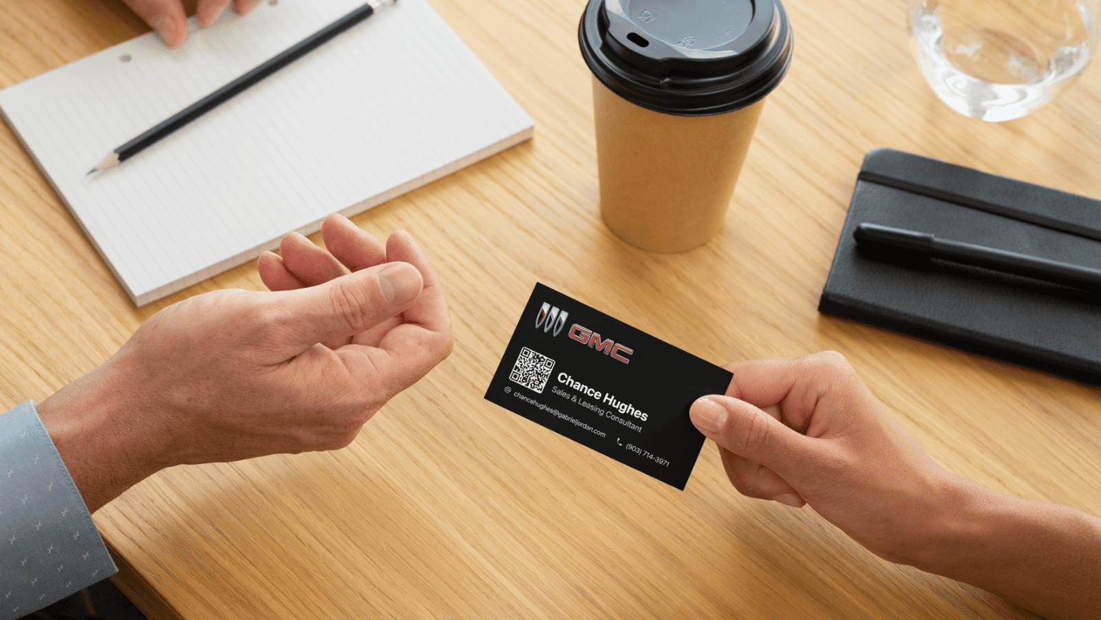A salesperson for GMC handing a business card to a customer